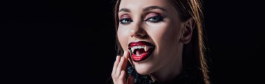 panoramic shot of scary vampire girl showing fangs in black gothic dress isolated on black clipart