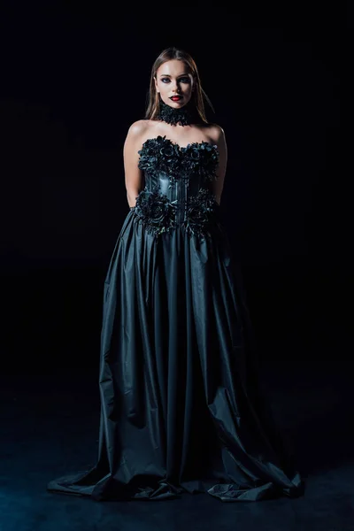 scary vampire girl in black Gothic dress on black background