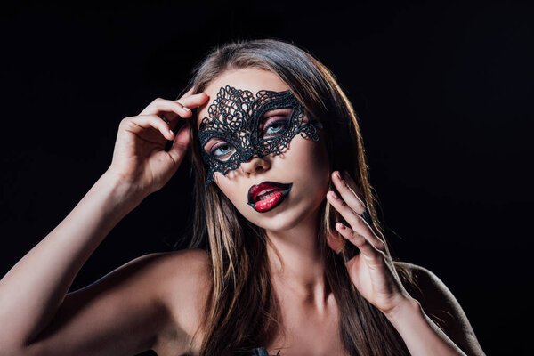 naked scary vampire girl in masquerade mask touching face isolated on black