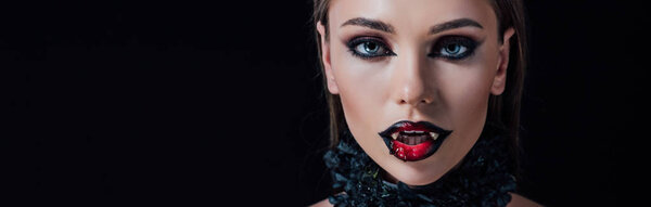 панорамный снимок страшной девушки-вампира с клыками, изолированными на черном

