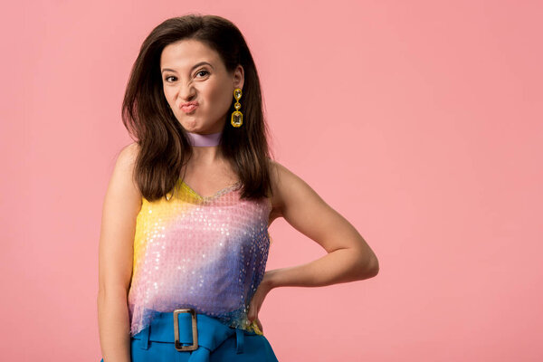 расстроен молодой стильной девушки диско с рукой на бедре grimacing изолированы на розовый
