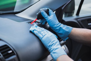 Lastik hava üfleyicisiyle havalandırma deliklerinin tozunu alan araba temizleyicisinin kırpılmış görüntüsü