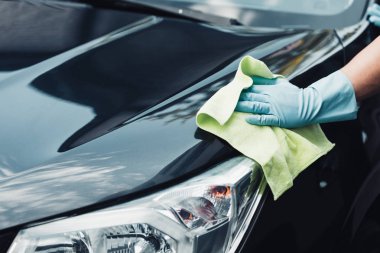 cropped view of car cleaner wiping black car with rag clipart