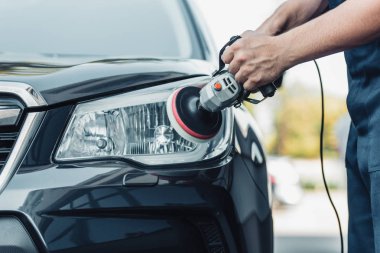 cropped view of car cleaner polishing headlamp with polish machine clipart