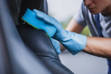 Araba temizleyicisinin araba koltuğunu süngerle silerken kısmi görüntüsü