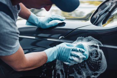 partial view of car cleaner washing car with sponge and detergent clipart