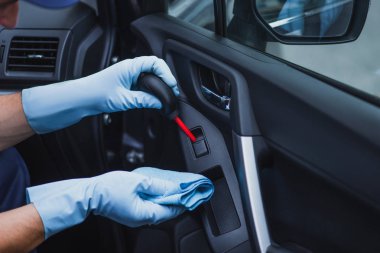 Araba temizleyicisinin plastik hava üfleyicisiyle araba kapısının tozunu alırken çekilmiş görüntüsü