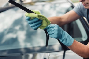 cropped view of car cleaner wiping windshield wiper with rag clipart