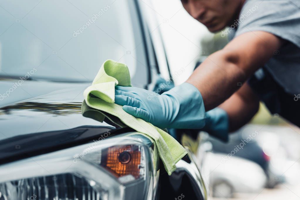 selective focus of car cleaner wiping capote with rag