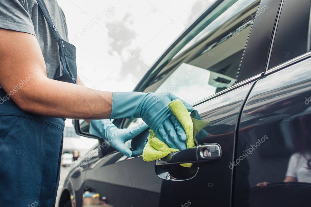 cropped view of car cleaner wiping car door with rag