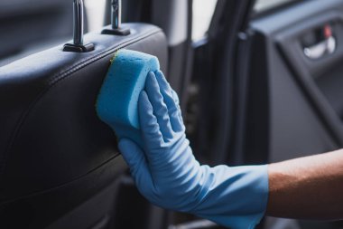 Plastik eldivenli araba temizleyicisinin oto koltuğunu temizlerken kısmi görüntüsü