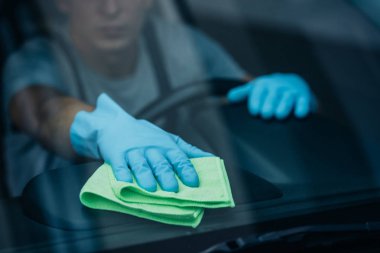 selective focus of car cleaner wiping dashboard near windshield clipart