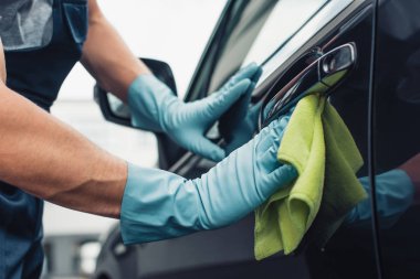 Araba temizleyicisinin araba kapısını bez parçasıyla silerken kısmi görüntüsü