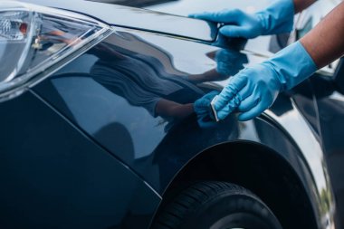 Lastik eldivenli araba temizleyicisinin araba cilalarkenki kısmi görüntüsü