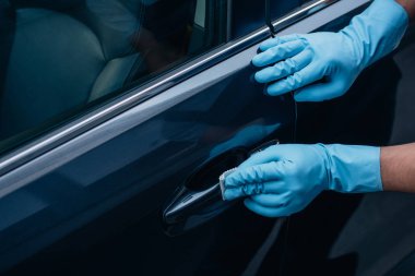 Siyah araba kapı kolunu cilalayan araba temizleyicisinin kısmi görüntüsü 