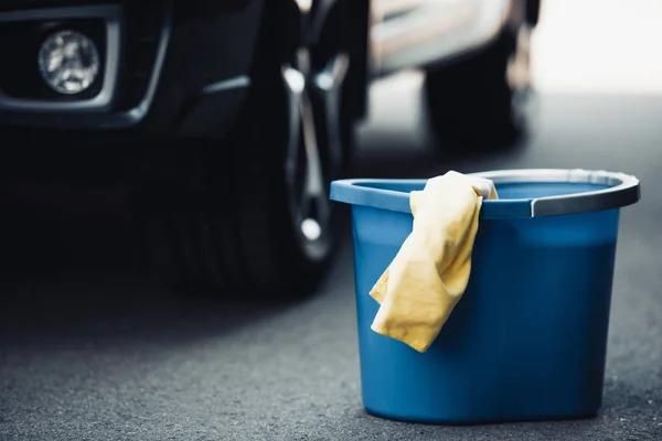 Blauer Eimer Und Gelber Lappen Auf Asphalt Neben Schwarzem Auto — Stockfoto