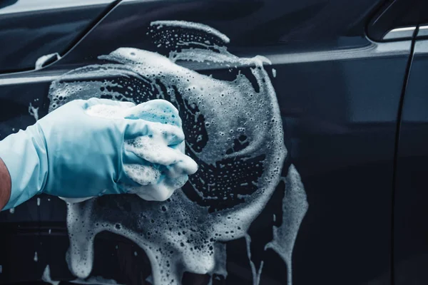 スポンジと洗剤で黒い車を洗う車のきれいなビューをトリミング — ストック写真