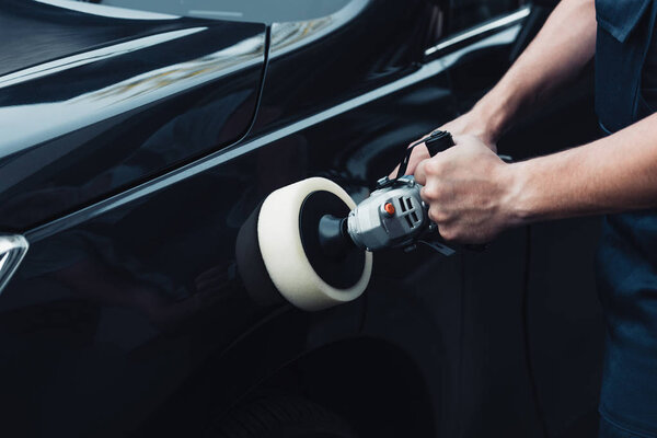 cropped view of car cleaner polishing black car with buffer machine