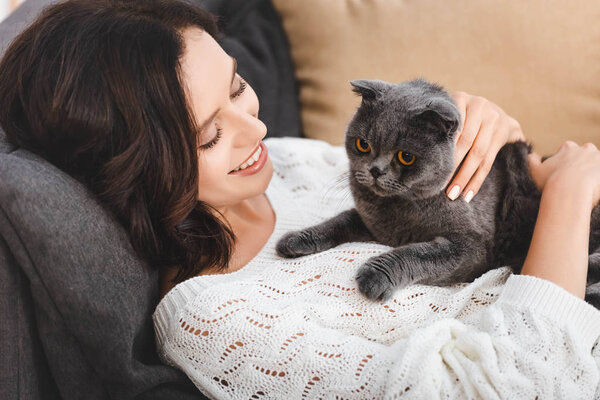 beautiful woman lying on sofa with scottish fold cat  