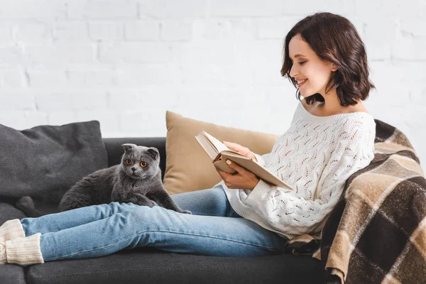 Menina Feliz Leitura Livro Com Escocês Dobra Gato Sofá — Fotografia de Stock