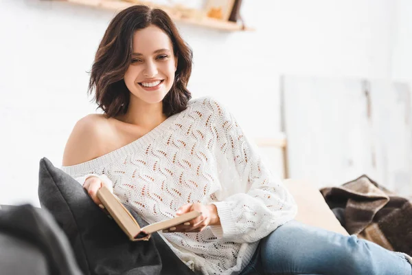 Morena Sorridente Menina Leitura Livro Sofá Casa — Fotografia de Stock