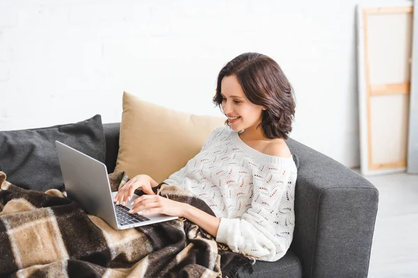 Uśmiechnięta Brunetka Dziewczyna Koc Pomocą Laptopa Kanapie Przytulnym Salonie — Zdjęcie stockowe