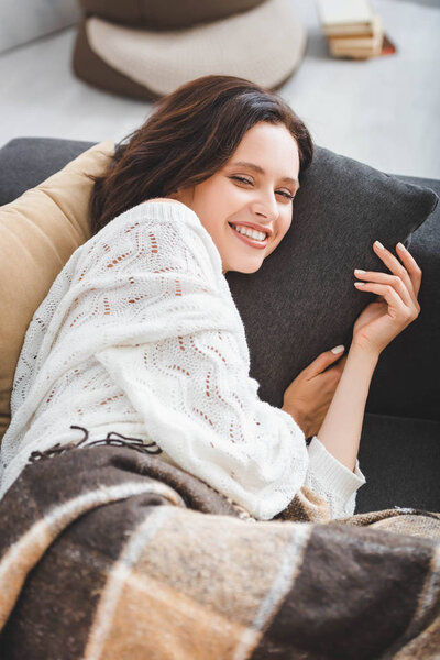 beautiful cheerful girl in blanket resting on sofa 