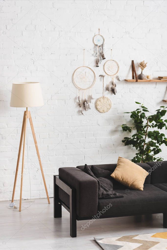 interior of cozy living room with couch, lamp and dream catchers on white wall