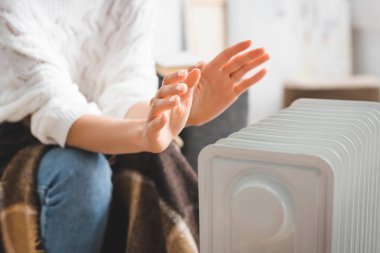 Soğuk odada ısıtıcıyla ısınan bir kızın kısmi görüntüsü