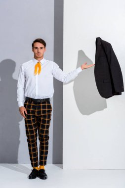 handsome man in checkered trousers standing and gesturing on white and grey  clipart