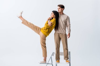 Yakışıklı adam sandalyede duruyor ve beyaz tenli çekici kıza sarılıyor. 