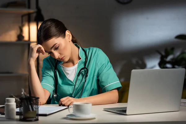 Attraktiv Och Trött Sjuksköterska Uniform Sitter Vid Bordet Och Tittar — Stockfoto