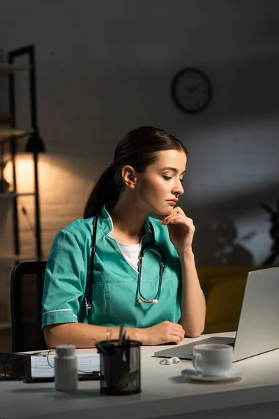 Enfermera Atractiva Uniforme Sentado Mesa Mirando Computadora Portátil Durante Turno — Foto de Stock