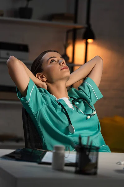 Ελκυστική Νοσοκόμα Στολή Κάθεται Στο Τραπέζι Σταυρωμένα Χέρια Κατά Διάρκεια — Φωτογραφία Αρχείου
