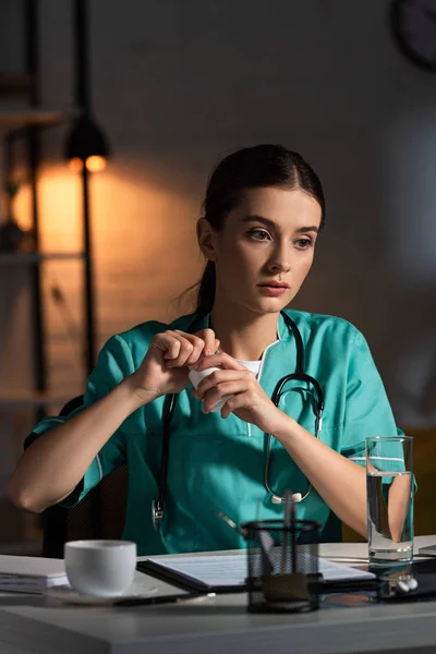 Ελκυστική Νοσοκόμα Στολή Κάθεται Στο Τραπέζι Και Άνοιγμα Μπουκάλι Χάπια — Φωτογραφία Αρχείου