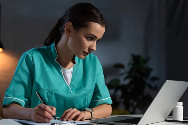 Enfermera Atractiva Uniforme Sentado Mesa Escritura Durante Turno Noche — Foto de Stock