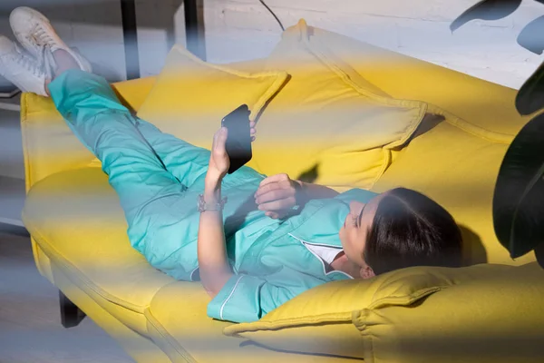 Selective Focus Nurse Uniform Lying Sofa Using Smartphone Night Shift — Stock Photo, Image
