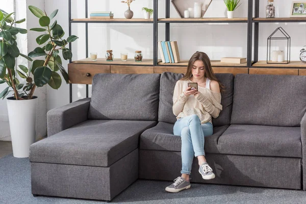 Chica Bonita Usando Teléfono Inteligente Mientras Está Sentado Sofá Sala — Foto de Stock