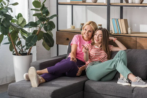 Alegre Chica Poiting Con Dedo Mientras Descansa Sofá Cerca Madre —  Fotos de Stock