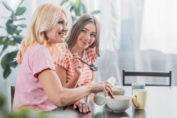 快乐的母亲和女儿坐在厨房桌子边吃早餐的选择性焦点 — 图库照片