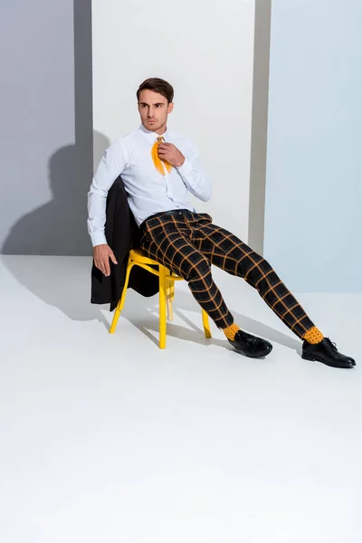 Young Man Checkered Trousers Sitting Yellow Chair White Grey — Stock Photo, Image