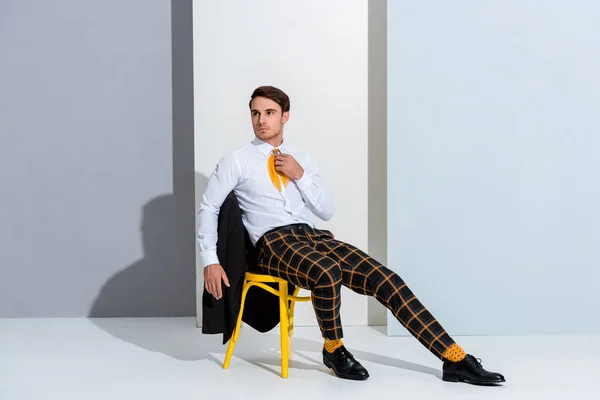 Man Checkered Trousers Sitting Yellow Chair White Grey — Stock Photo, Image