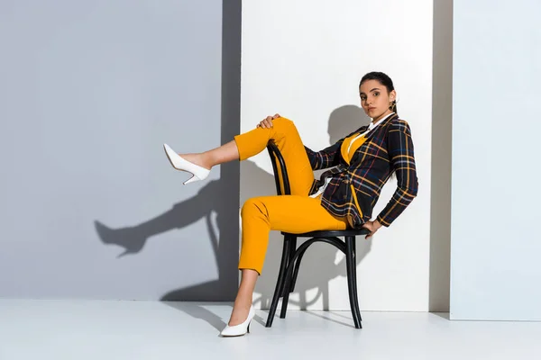 Atraente Jovem Mulher Sentada Cadeira Posando Cinza Branco — Fotografia de Stock