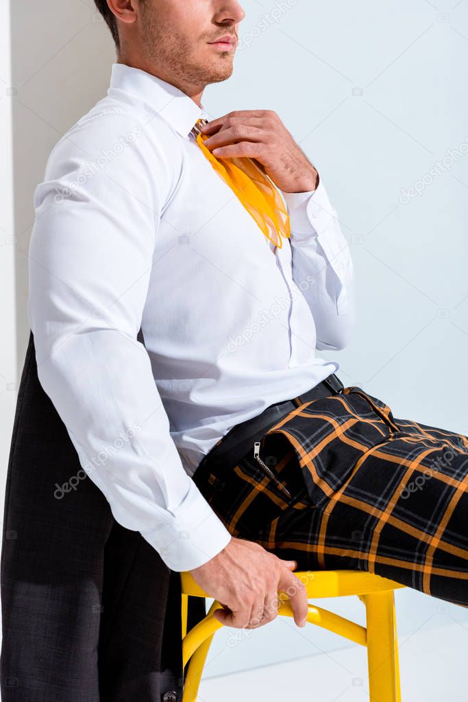 cropped view of man in checkered trousers sitting on white 