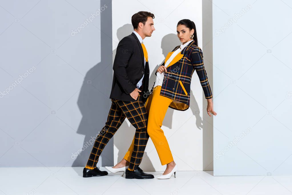 stylish man and woman posing on white and grey 