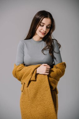 Bej ceketli çekici, zarif bir kadın. Gri üzerinde soyutlanmış.