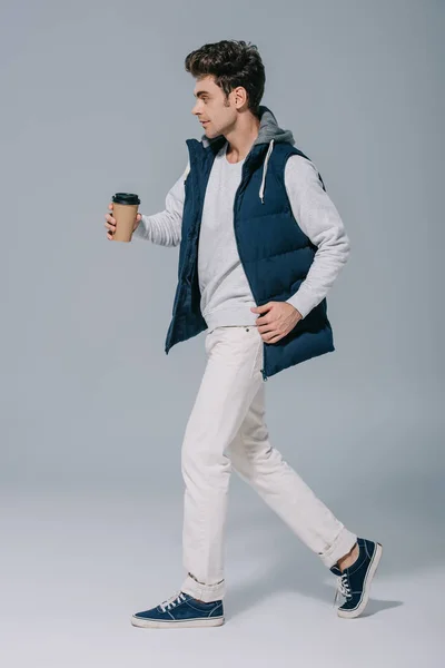 穿着保暖背心 穿着时髦的男人 一边喝咖啡一边走着 一边走着灰蒙蒙的 — 图库照片