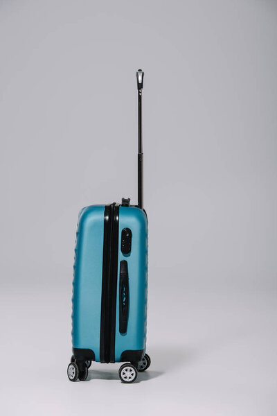 blue plastic suitcase for journey standing on grey