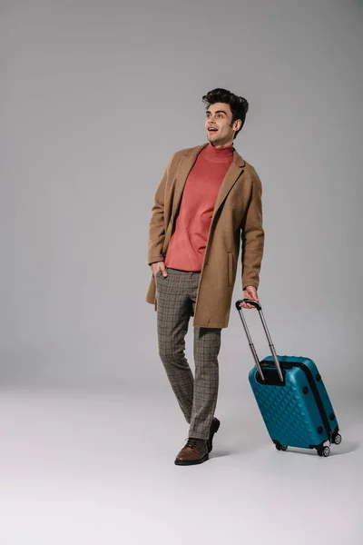 Aufgeregter Mann Beigem Mantel Geht Mit Koffer Auf Grau — Stockfoto