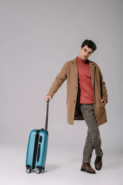 Hombre Elegante Posando Abrigo Beige Con Maleta Azul Sobre Gris — Foto de Stock